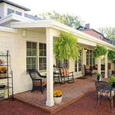 a patio with chairs, tables and potted plants on the side of the house