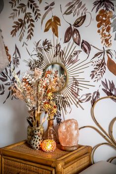 a table topped with a vase filled with lots of flowers next to a wall mounted mirror