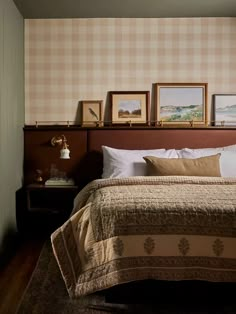 a bed sitting in a bedroom next to two framed pictures on the wall above it