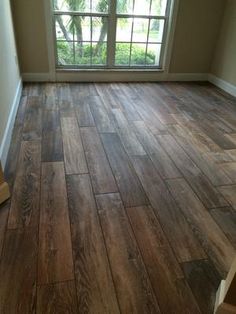 an empty room with wood flooring and large window in the corner on one side