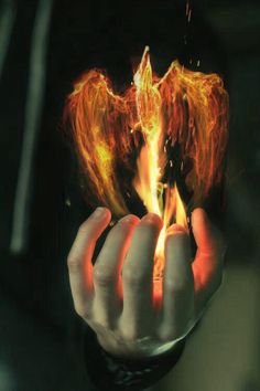 a hand holding a burning object in it's right hand with flames coming out of it