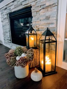 two lit candles sitting on top of a table next to a vase with flowers and pumpkins