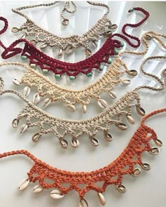 several crocheted necklaces are displayed on a white surface, including one with beads