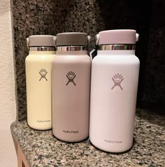 three hydro flasks sitting on top of a granite countertop next to each other