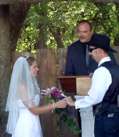 the bride and groom are getting married in front of an outdoor alter with trees behind them