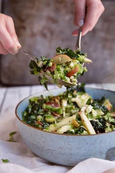 a person is spooning some food out of a bowl with broccoli and apples