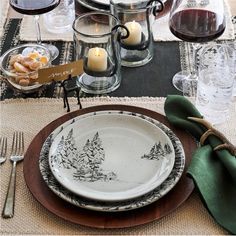 a table set with plates, silverware and candles