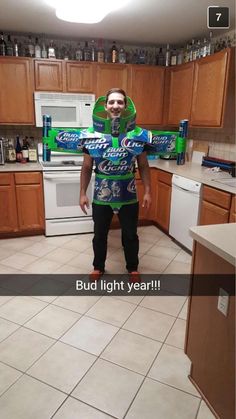 a man standing in a kitchen wearing a green and blue shirt with the words bud light year on it