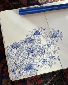 a notebook with some flowers drawn on it and a blue pen resting on the page