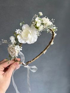 a hand holding a flower crown with white flowers