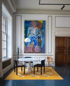 a painting hangs on the wall above a table with chairs