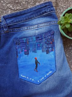 a pair of blue jeans with an image of a person walking on the street in front of a potted plant