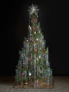 a lighted christmas tree in front of a black background