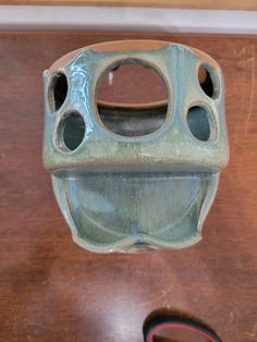 a green vase sitting on top of a wooden table next to a pair of scissors