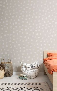 a bedroom with an orange bed and white polka dot wallpaper, along with two baskets on the floor