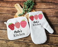 two oven mitts with strawberries on them and the words mud's kitchen