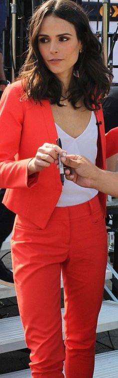 a woman in an orange suit is looking at her cell phone