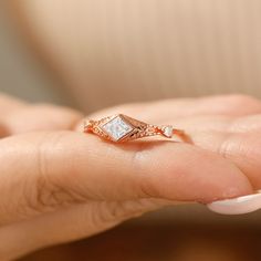 a woman's hand holding an engagement ring with a diamond in the middle and two diamonds on each side