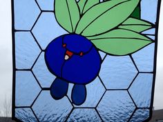 a stained glass window with a blue bird holding a green leaf on it's head