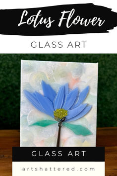 a blue flower sitting on top of a wooden table next to a glass art sign