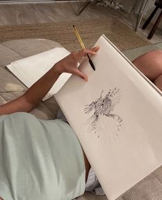 a person laying on the ground with a pencil in their hand and drawing something else