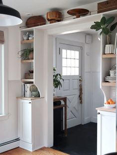 an open door leading to a kitchen with white walls and wooden flooring on the other side