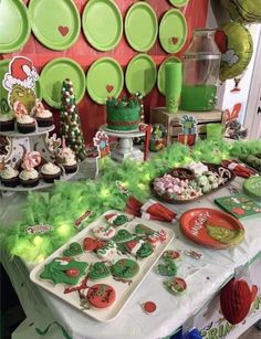 a table topped with lots of desserts and plates covered in green frosted icing