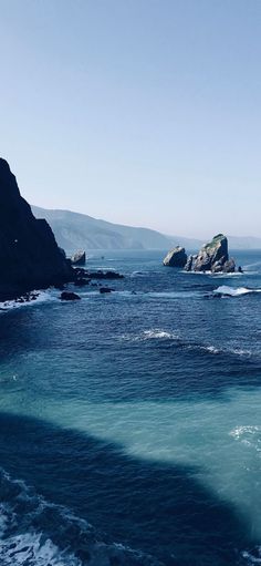 the water is very blue and there are two large rocks in the distance