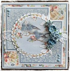 a close up of a card with flowers and two birds on the front, surrounded by lace