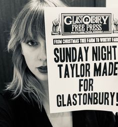 a woman holding up a sign that says sunday night taylor made for glastonbury