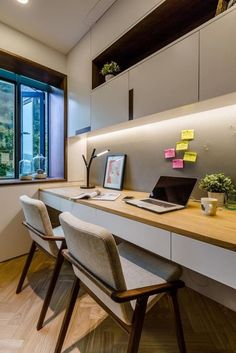 an office with two desks and chairs in front of a large window that looks out onto the city