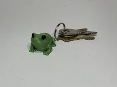 a green frog keychain with two keys attached to it's back end