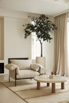 a living room with a tree in the corner and curtains on the window sill