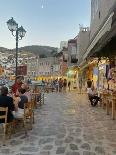 people are sitting at tables in the middle of an outdoor area with shops and restaurants