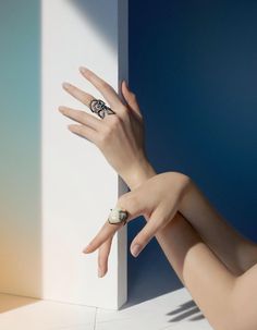 a woman's hand reaching out from behind a white wall with a ring on it