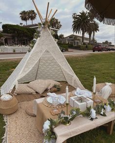 a teepee tent set up on the grass with candles, plates and napkins