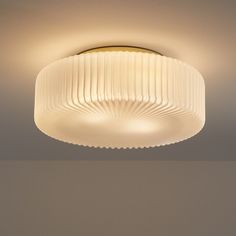 a ceiling light with pleated glass coverings on the top and bottom, in a room