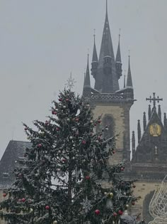 a christmas tree in front of a church with a clock on it's side