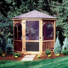 a wooden gazebo sitting in the middle of a lush green field