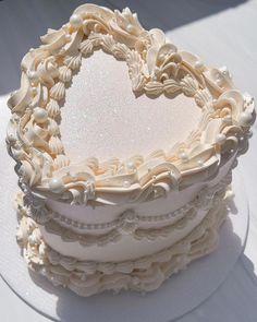 a heart shaped cake sitting on top of a white table covered in frosted icing