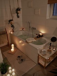 a bathtub with candles on the floor next to it and a book in the tub