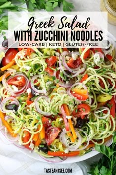 greek salad with zucchini noodles and tomatoes in a white bowl on a table