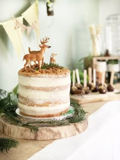 a cake decorated with deer figurines on top of a table