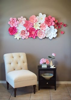 a white chair sitting in front of a wall with pink and white flowers on it