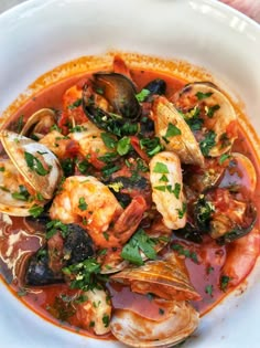 a white bowl filled with clams and sauce on top of a table next to a fork