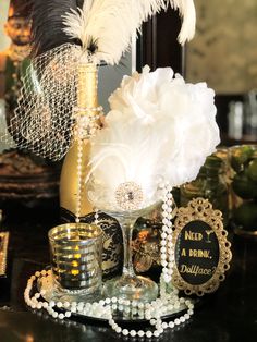 a table topped with a vase filled with white flowers and lots of feathers on top of it