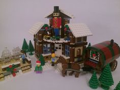 a lego house with people and animals in the front yard, surrounded by christmas trees