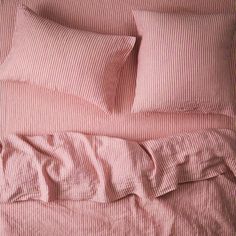 a bed with pink sheets and pillows on it