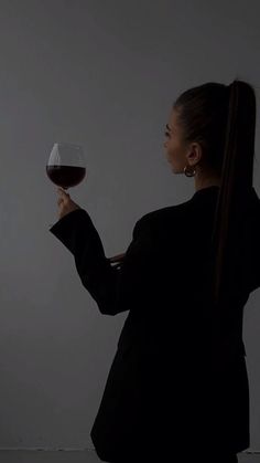 a woman holding a glass of wine in one hand and looking up at the sky