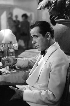 a black and white photo of a man sitting at a table in front of a lamp